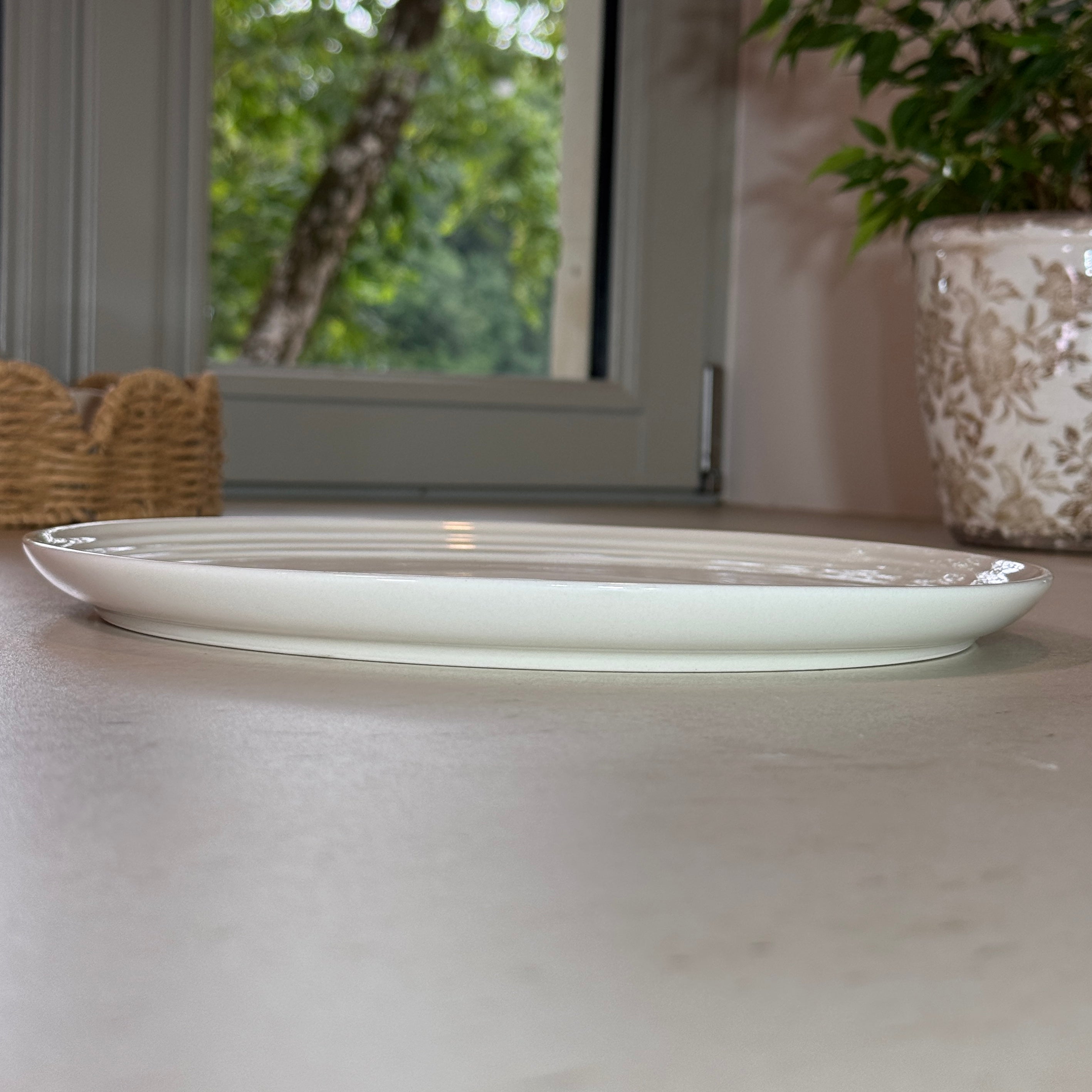 Vue de profil des assiettes en céramique émaillée blanc avec finition brillante et rebord légèrement relevé.