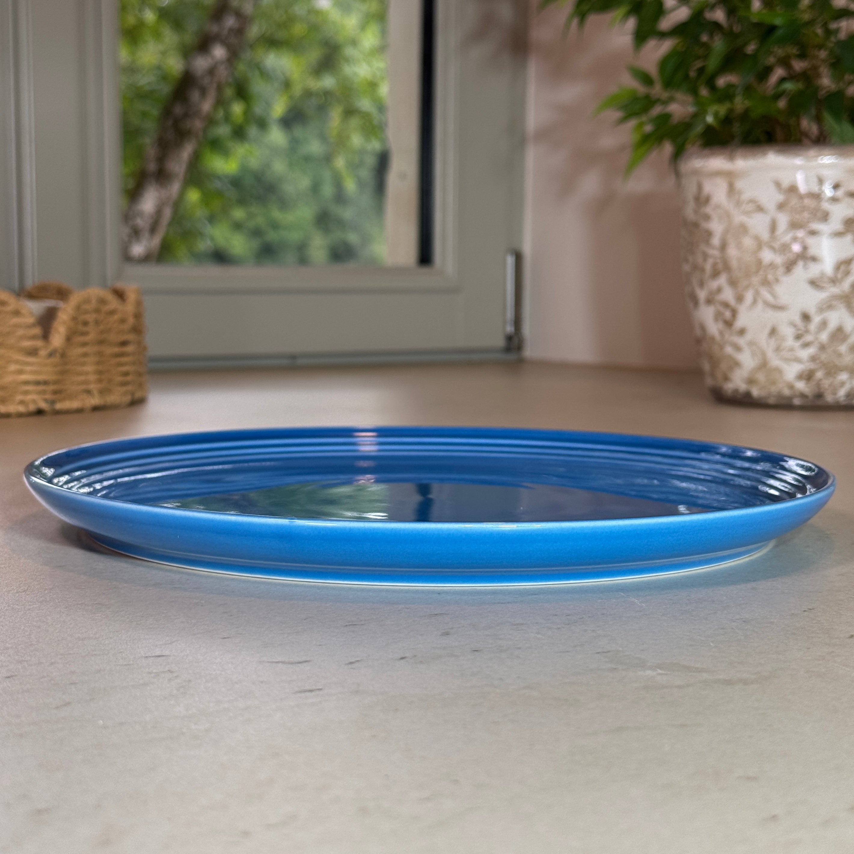 Vue de profil des assiettes en céramique émaillée bleu avec finition brillante et rebord légèrement relevé.