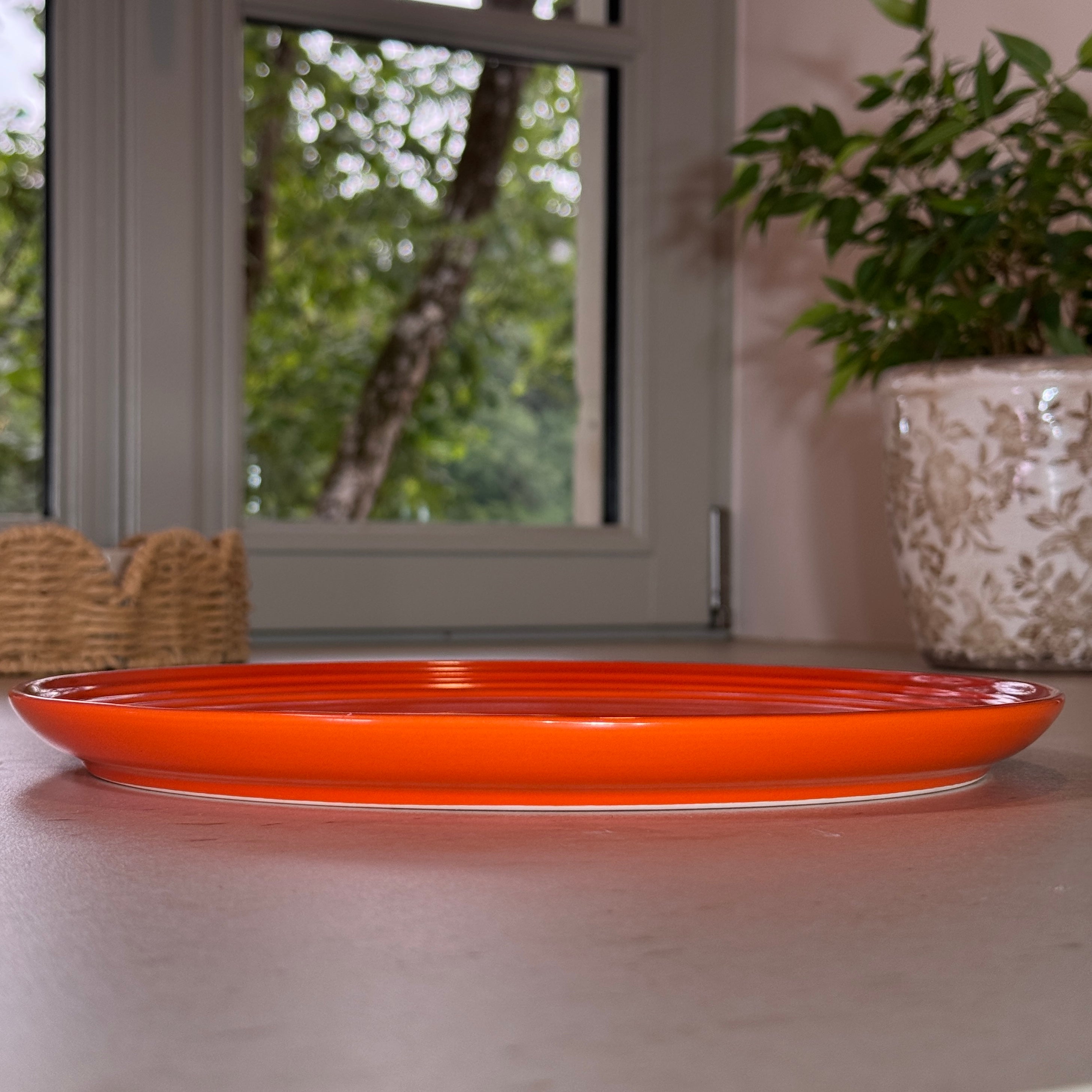 Vue de profil des assiettes en céramique émaillée orange avec finition brillante et rebord légèrement relevé.