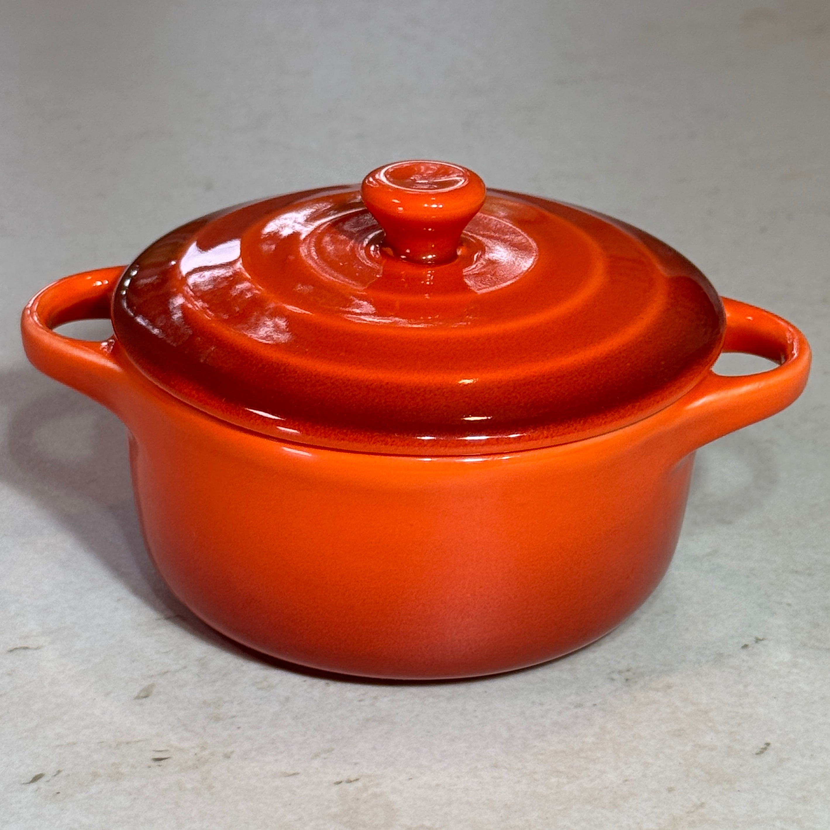 Mini cocotte en céramique émaillée orange au design traditionnel avec trois cercles sur le couvercle.