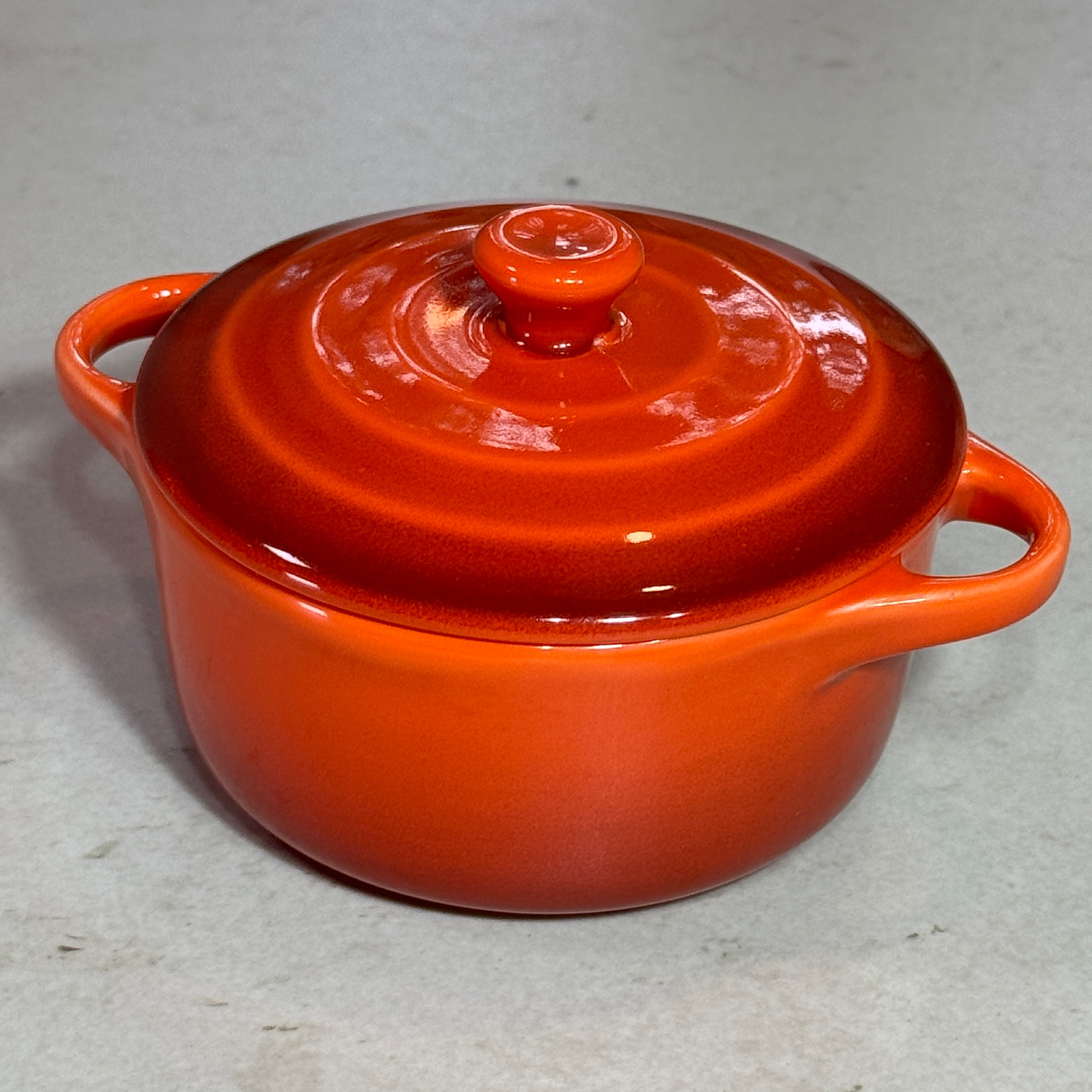 Vue de profil de la mini cocotte en céramique émaillée orange 220 ml avec poignées et couvercle.