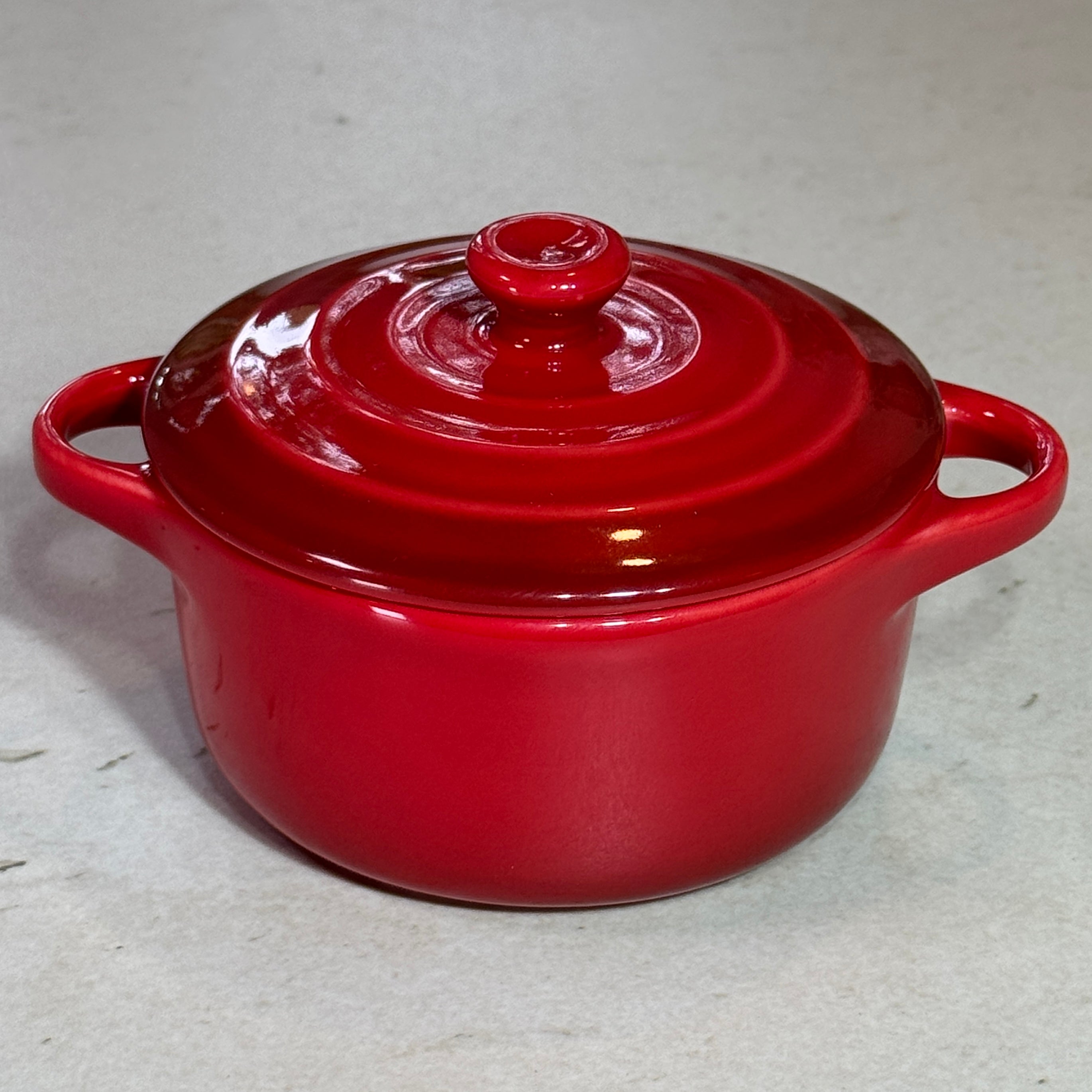 Mini cocotte en céramique émaillée rouge au design traditionnel avec trois cercles sur le couvercle.