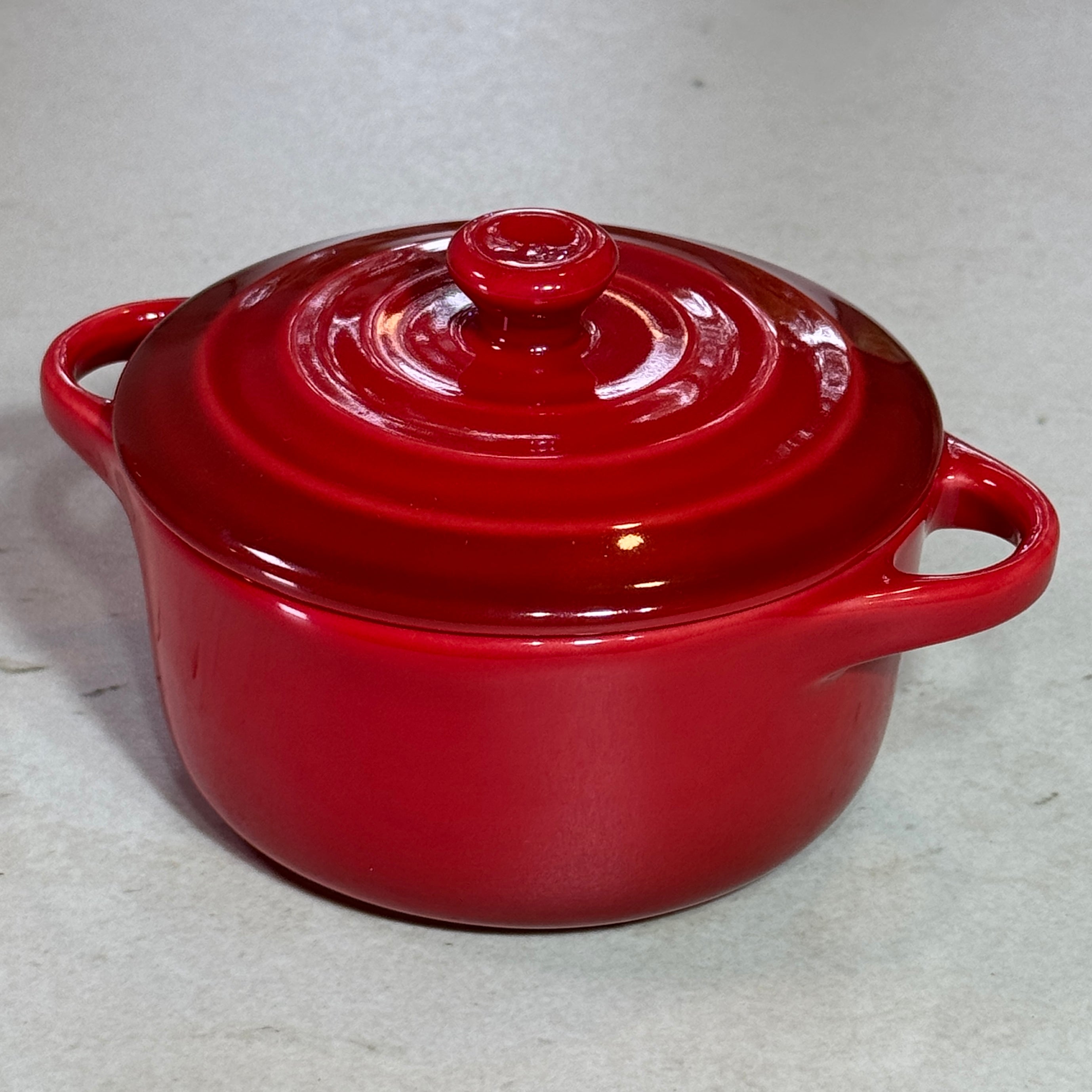 Vue de profil de la mini cocotte en céramique émaillée rouge 220 ml avec poignées et couvercle.