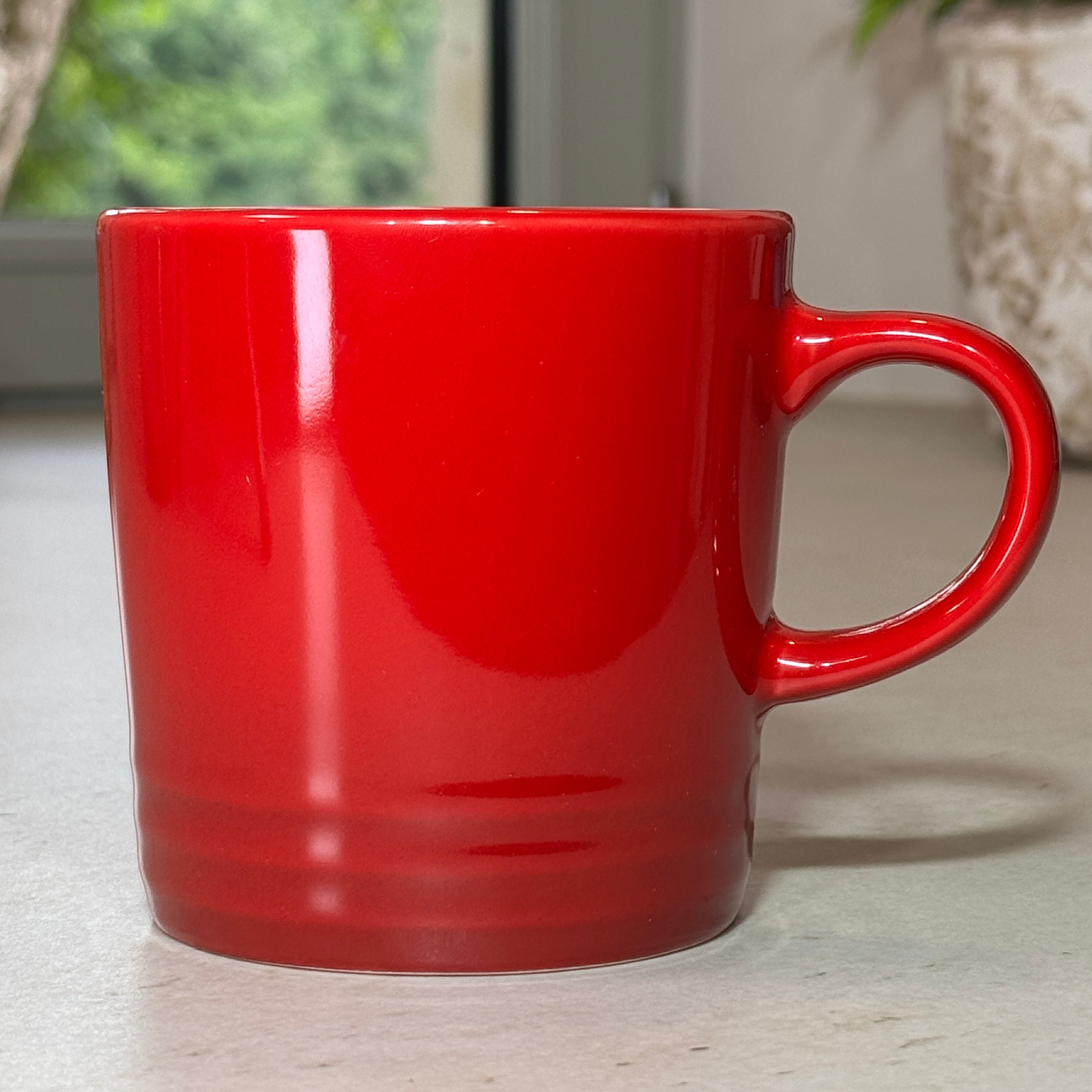 Mug en céramique émaillée rouge 350 ml au design intemporel avec trois cercles en relief à la base.