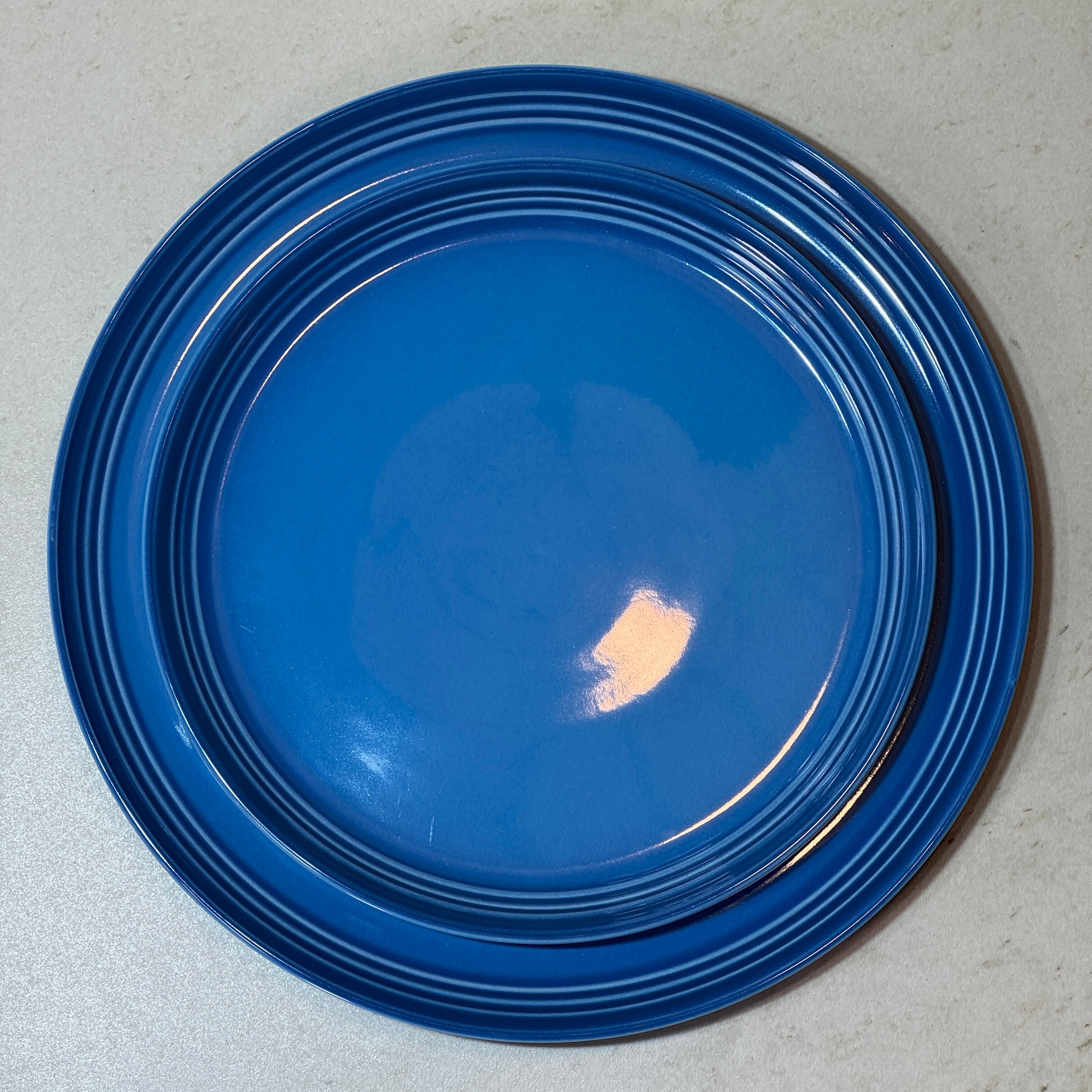 Service d'assiettes en céramique émaillée bleu comprenant une assiette plate 27 cm et une assiette à dessert 22 cm.