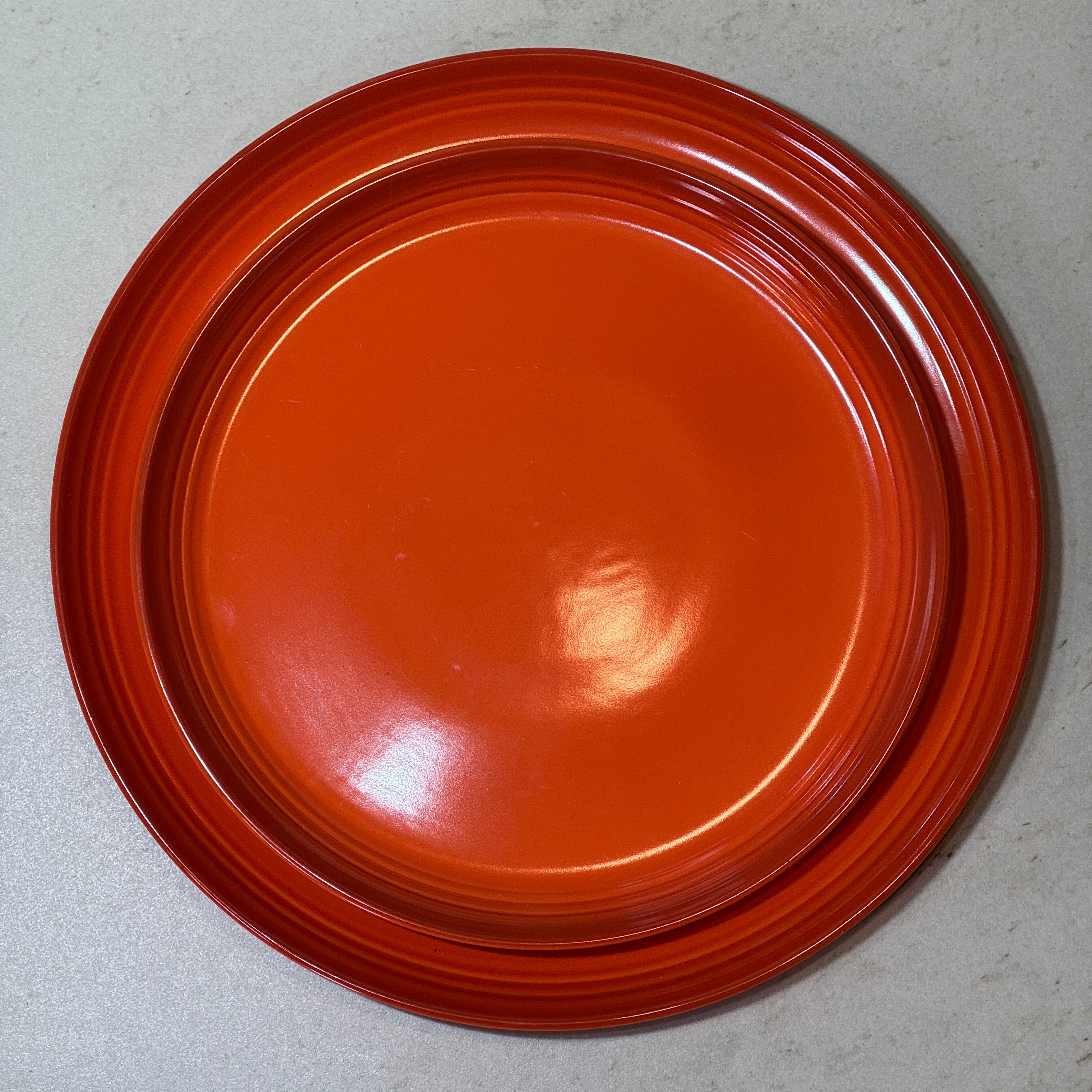 Service d'assiettes en céramique émaillée orange comprenant une assiette plate 27 cm et une assiette à dessert 22 cm.