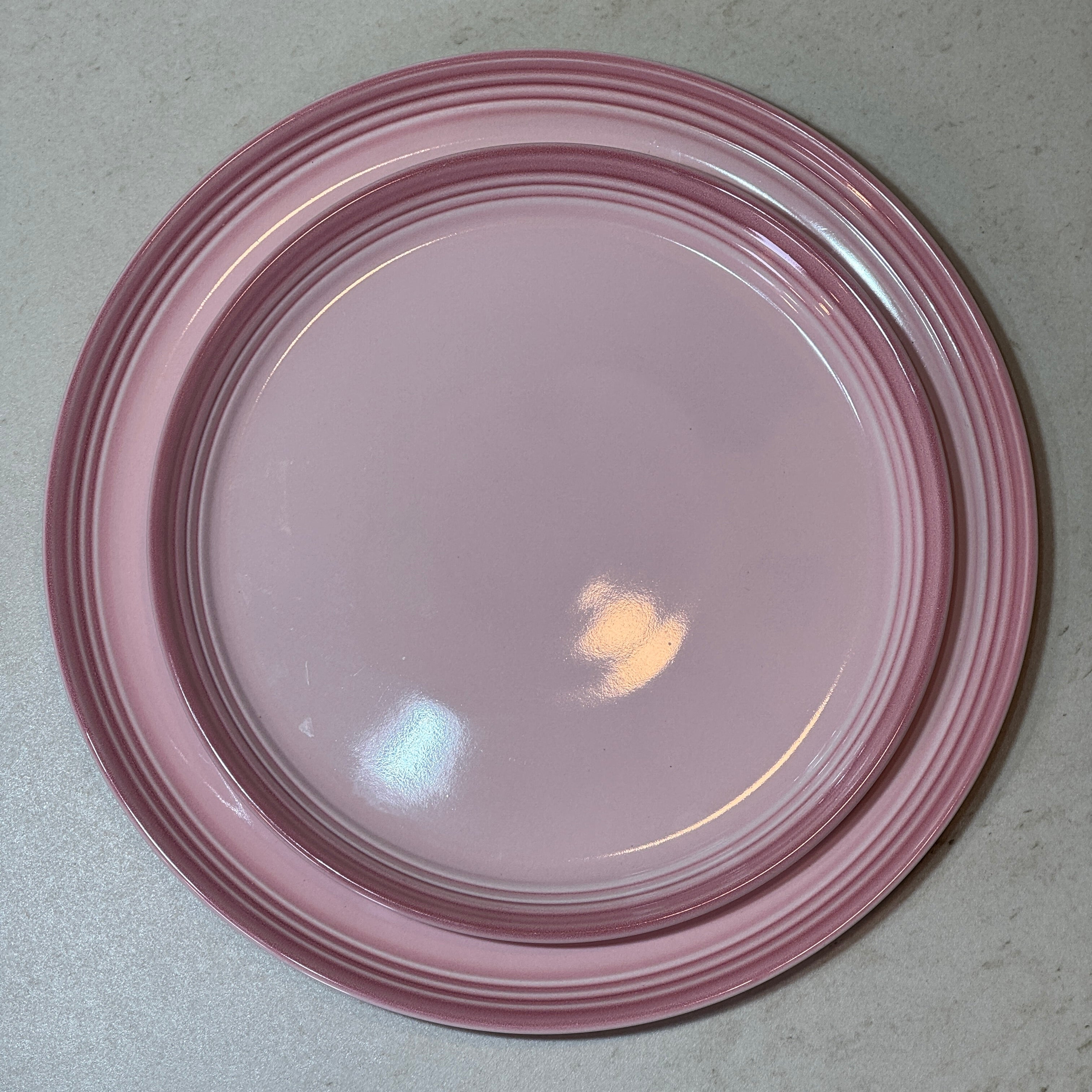 Service d'assiettes en céramique émaillée rose comprenant une assiette plate 27 cm et une assiette à dessert 22 cm.