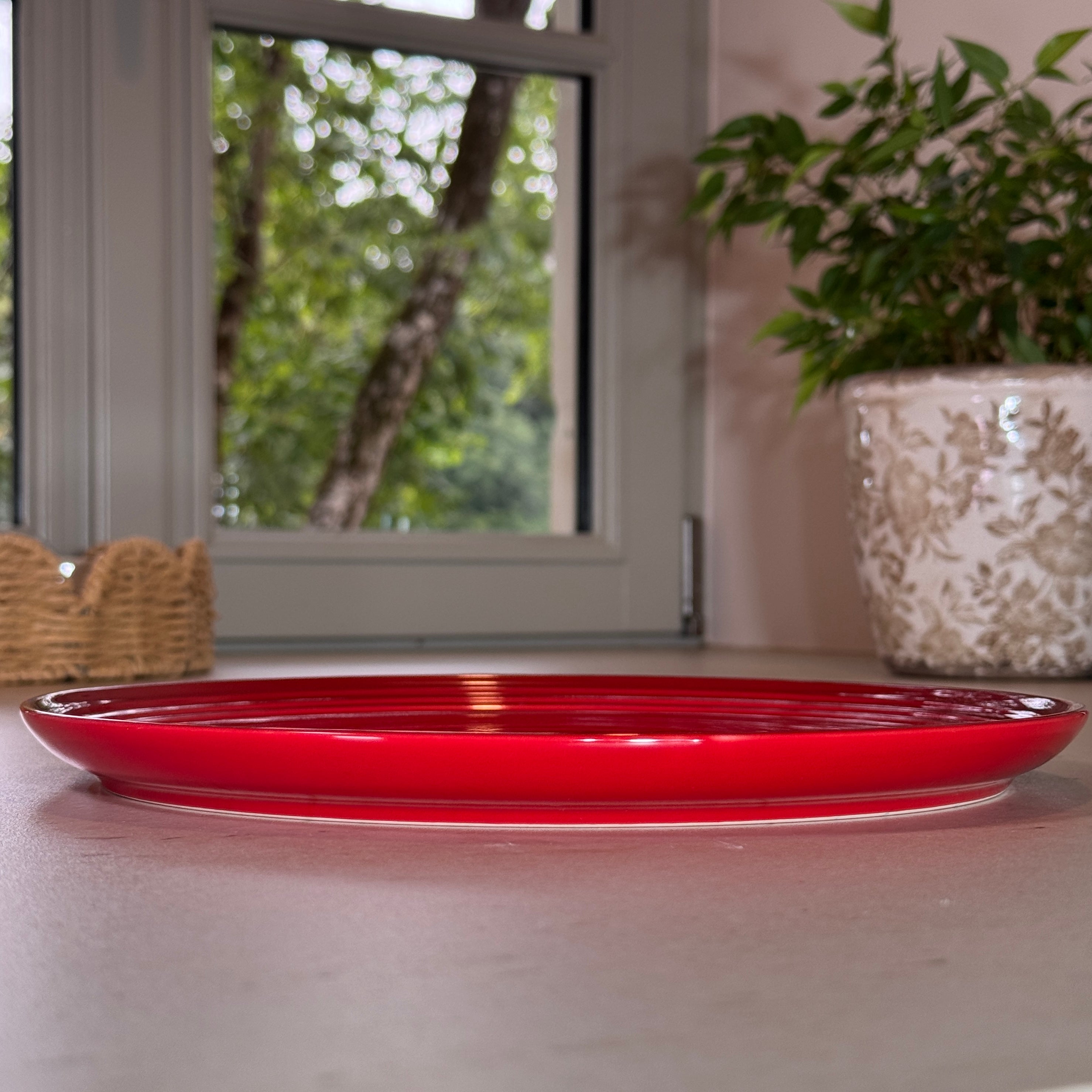 Vue de profil des assiettes en céramique émaillée rouge avec finition brillante et rebord légèrement relevé.