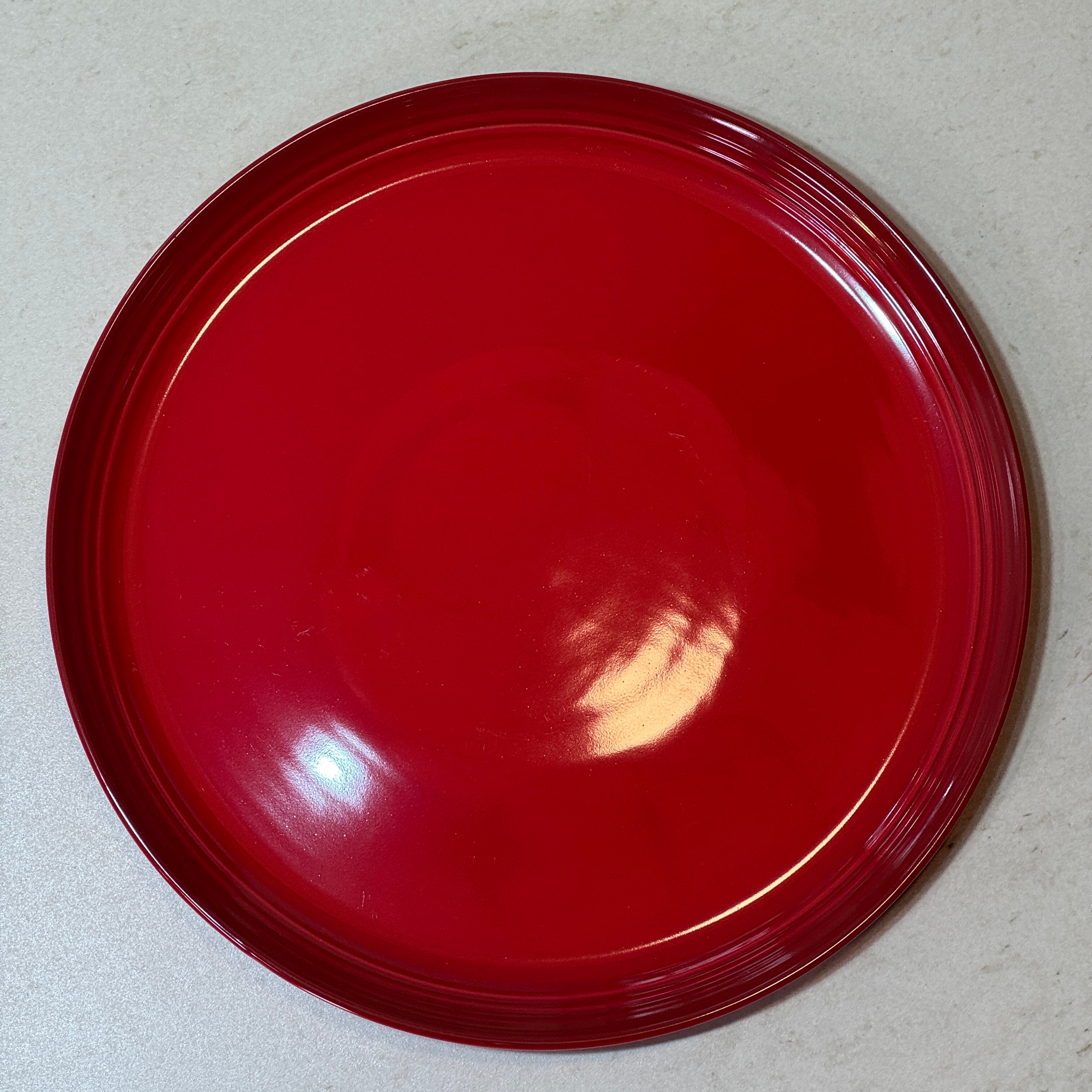 Assiette plate 27 cm en céramique émaillée rouge, parfaite pour les plats principaux, grillades, pâtes et salades.