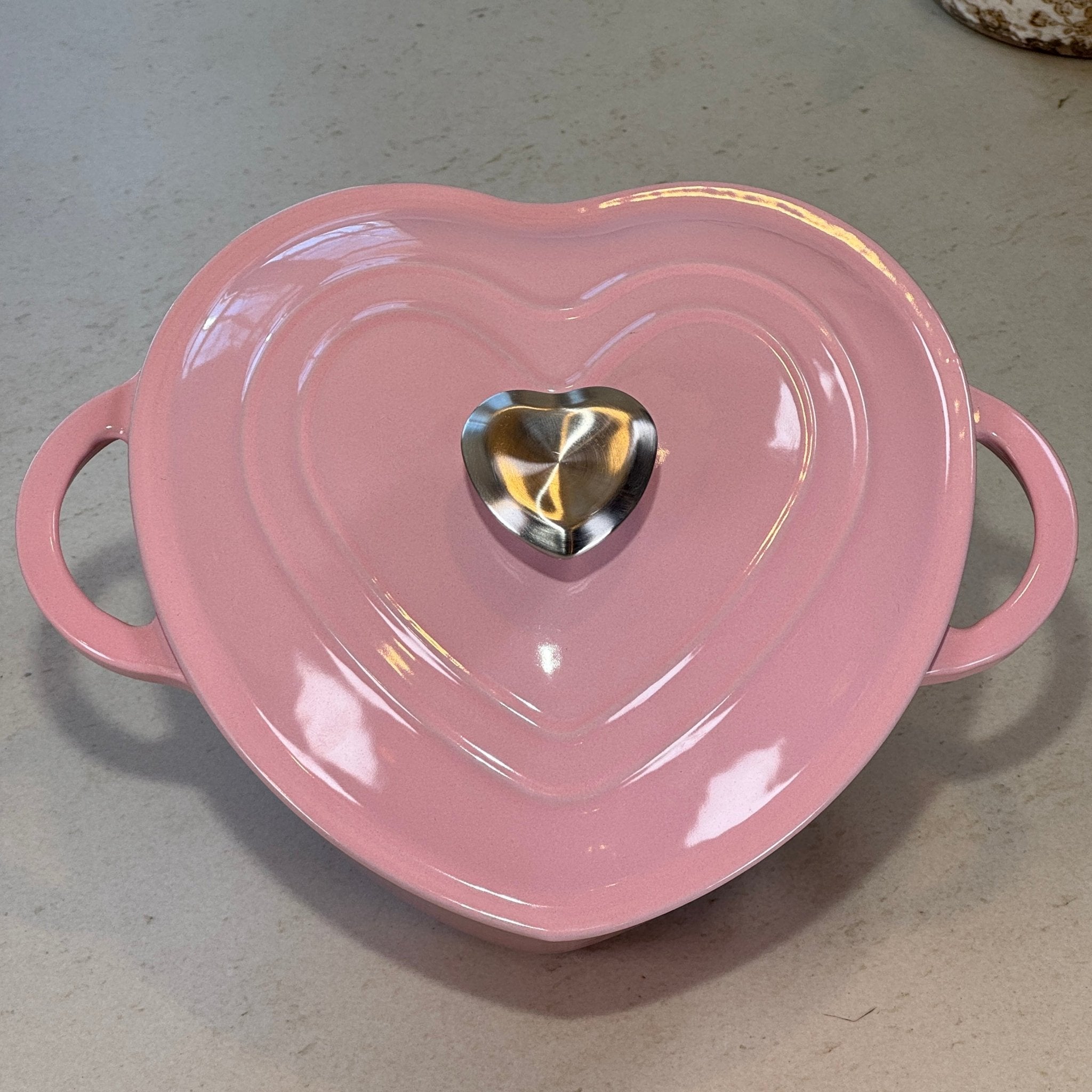 Cocotte en fonte émaillée rose en forme de cœur posée sur plan de cuisine