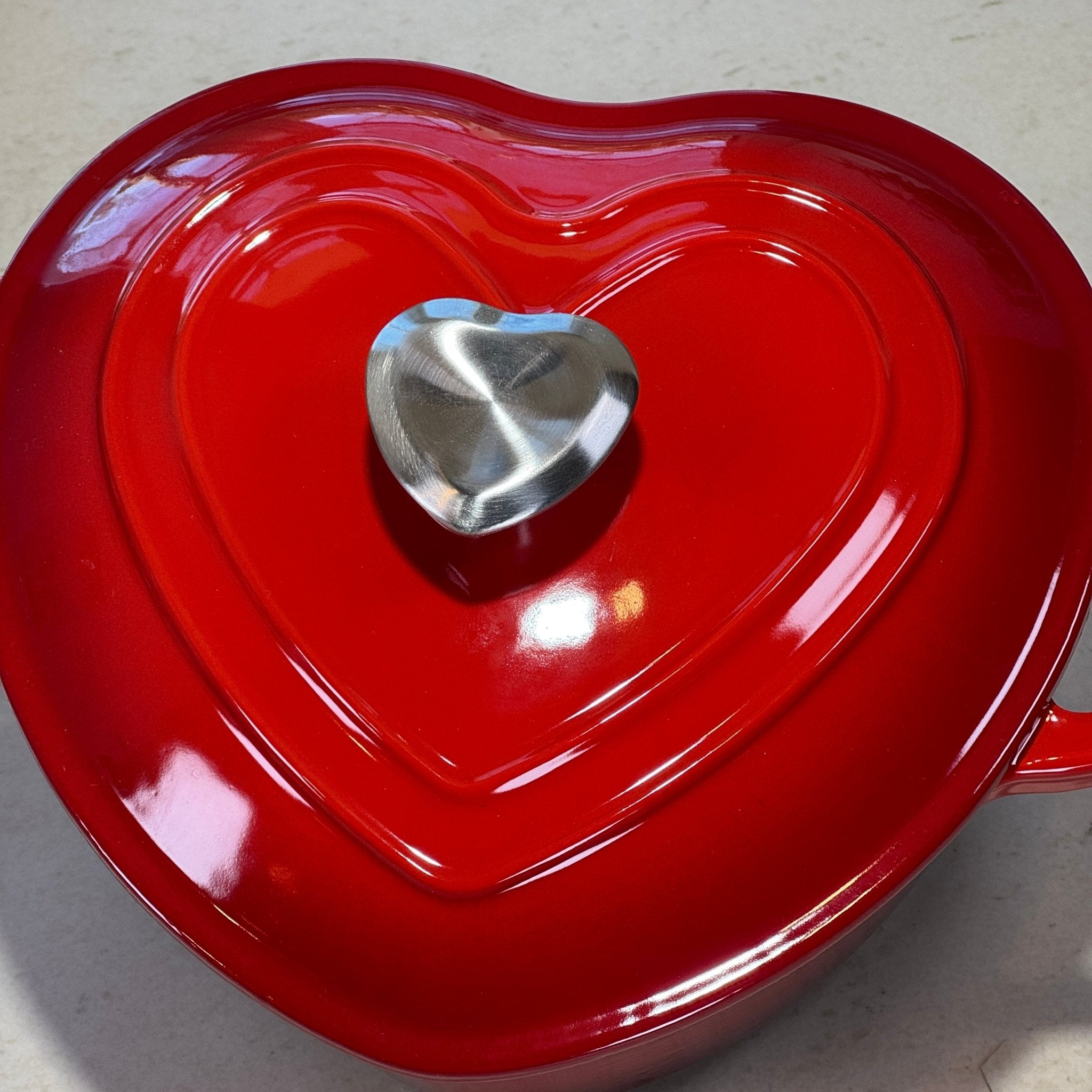 Détail du couvercle cœur et du bouton inox d’une cocotte en fonte rouge Mamie Cocottes