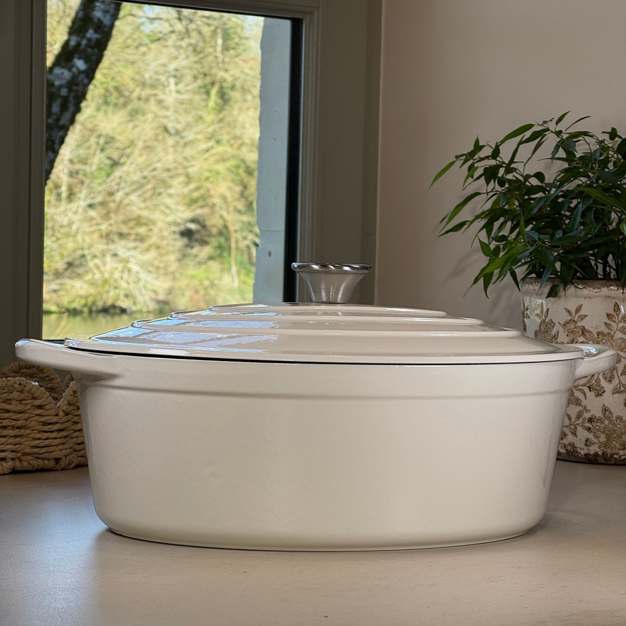 Cocotte ovale en fonte émaillée blanc vanille posée sur plan de cuisine moderne