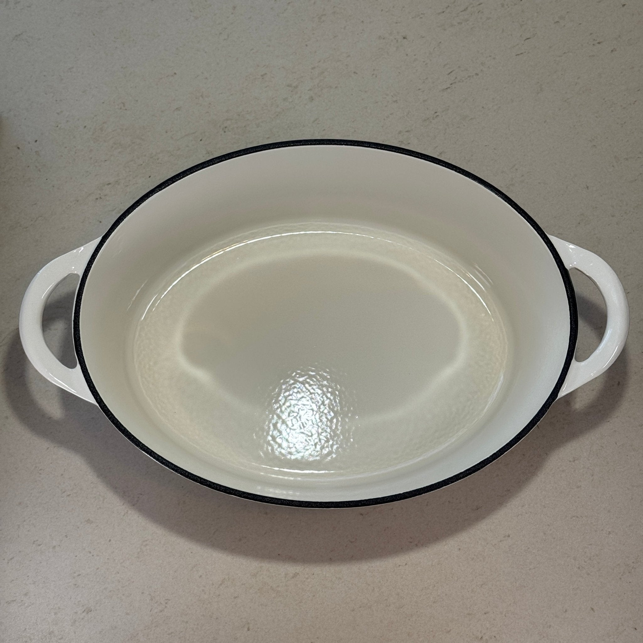 Intérieur d’une cocotte ovale en fonte émaillée blanc vanille pour cuisson mijotée au four ou sur plaque
