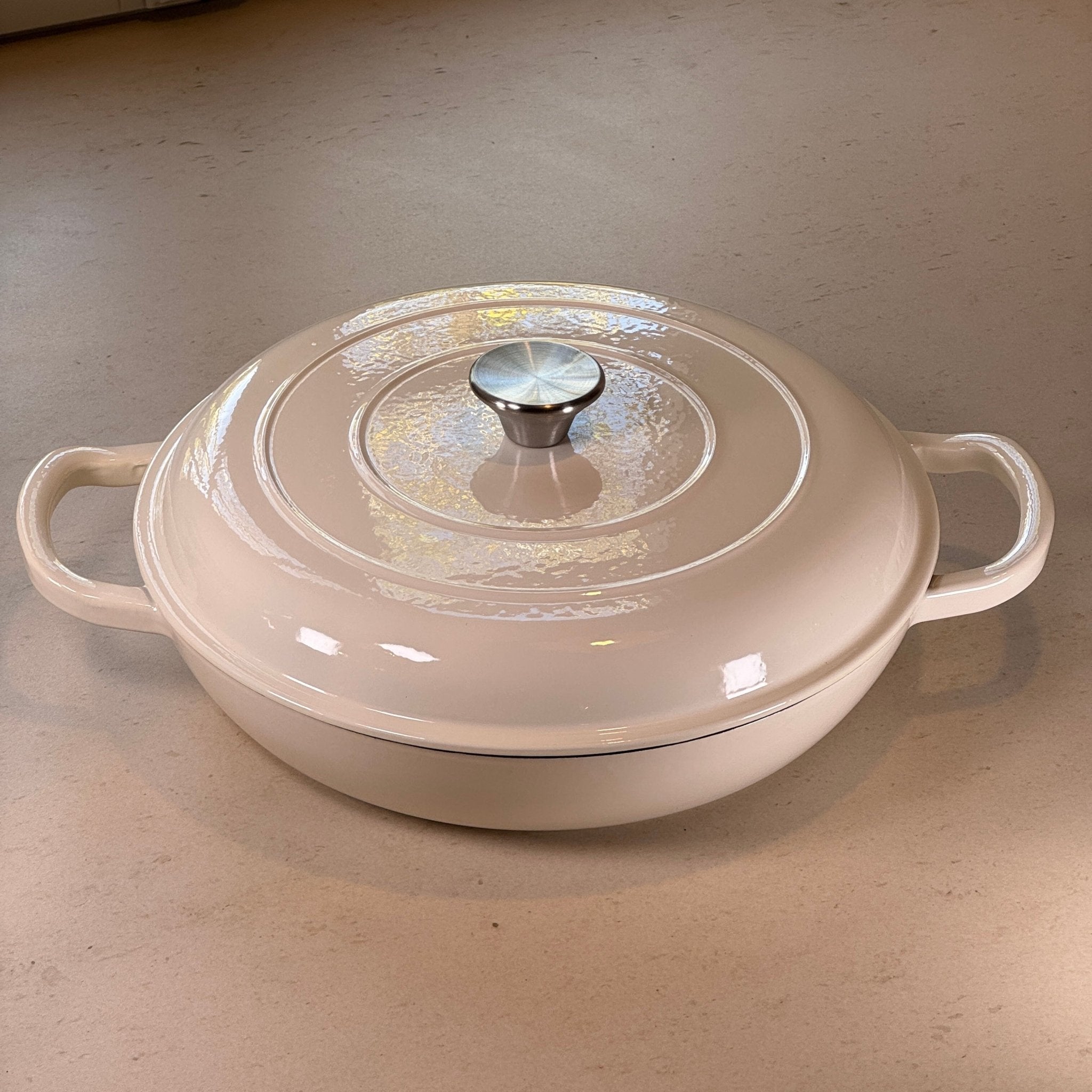 Faitout en fonte émaillée blanc vanille avec couvercle à picots assurant un arrosage naturel des plats pendant la cuisson