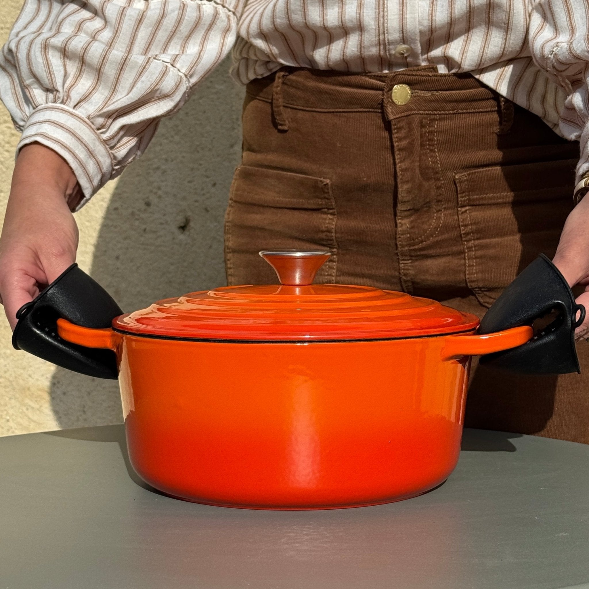 Paire de manique silicone noir attrapant une cocotte en fonte émaillée orange