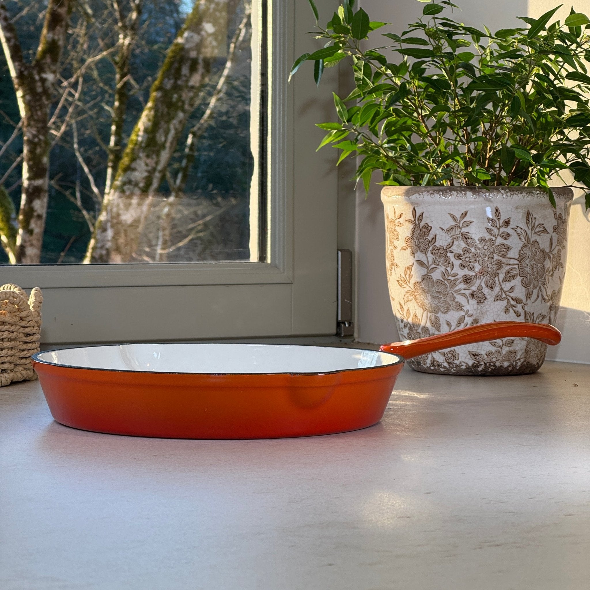 Poêle en fonte émaillée orange design posée sur plan de travail de cuisine moderne