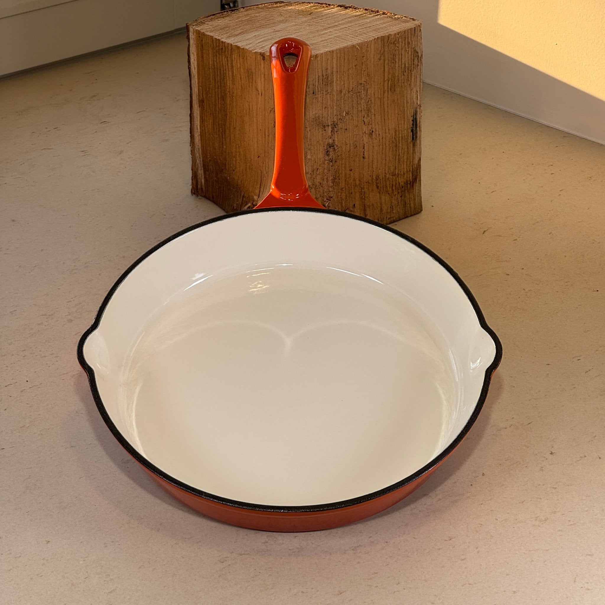 Poêle en fonte émaillée orange avec intérieur blanc idéale pour saisir et cuire les aliments
