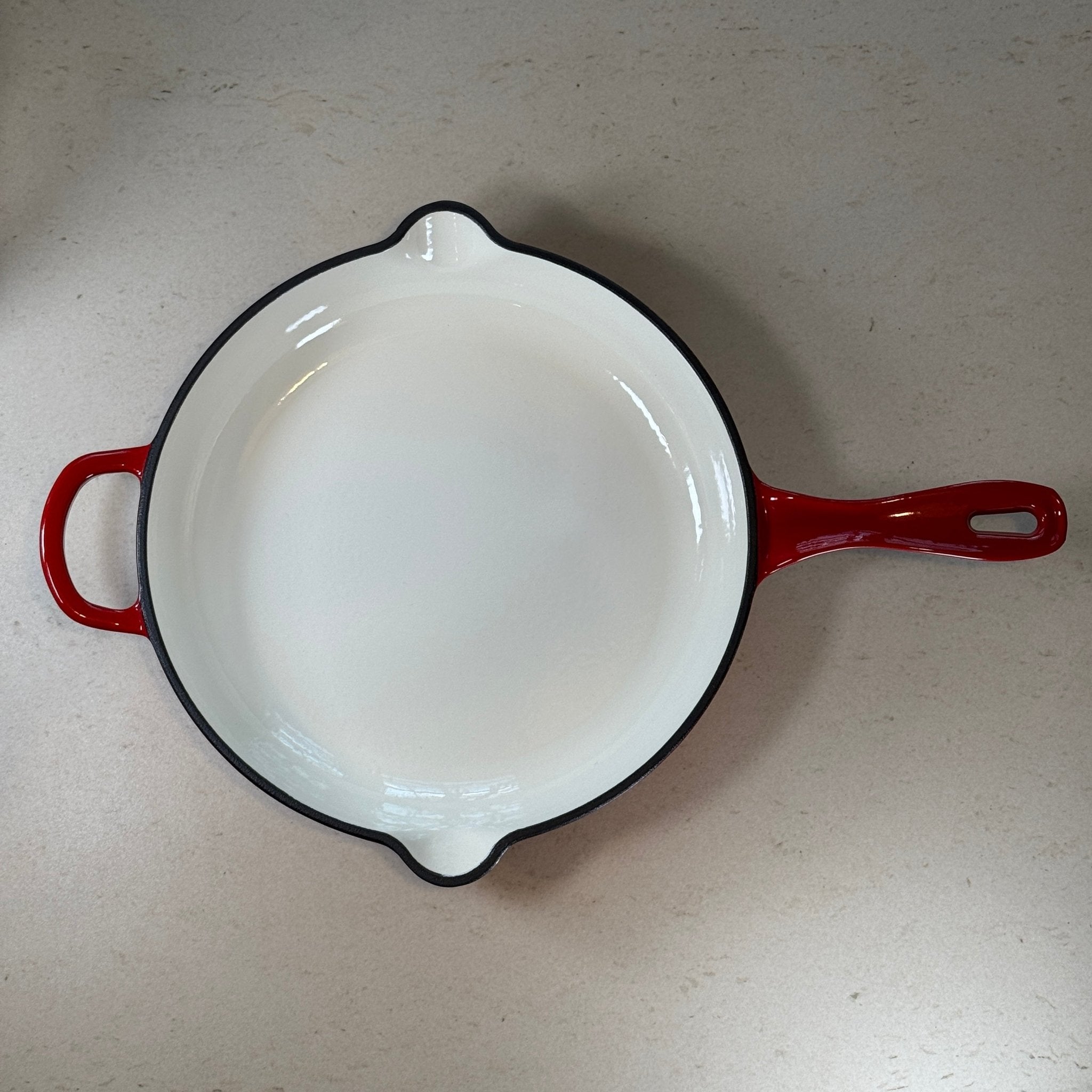 Intérieur anti adhésif clair d’une poêle en fonte émaillée Rouge Cerise pour cuisson homogène et saisie parfaite