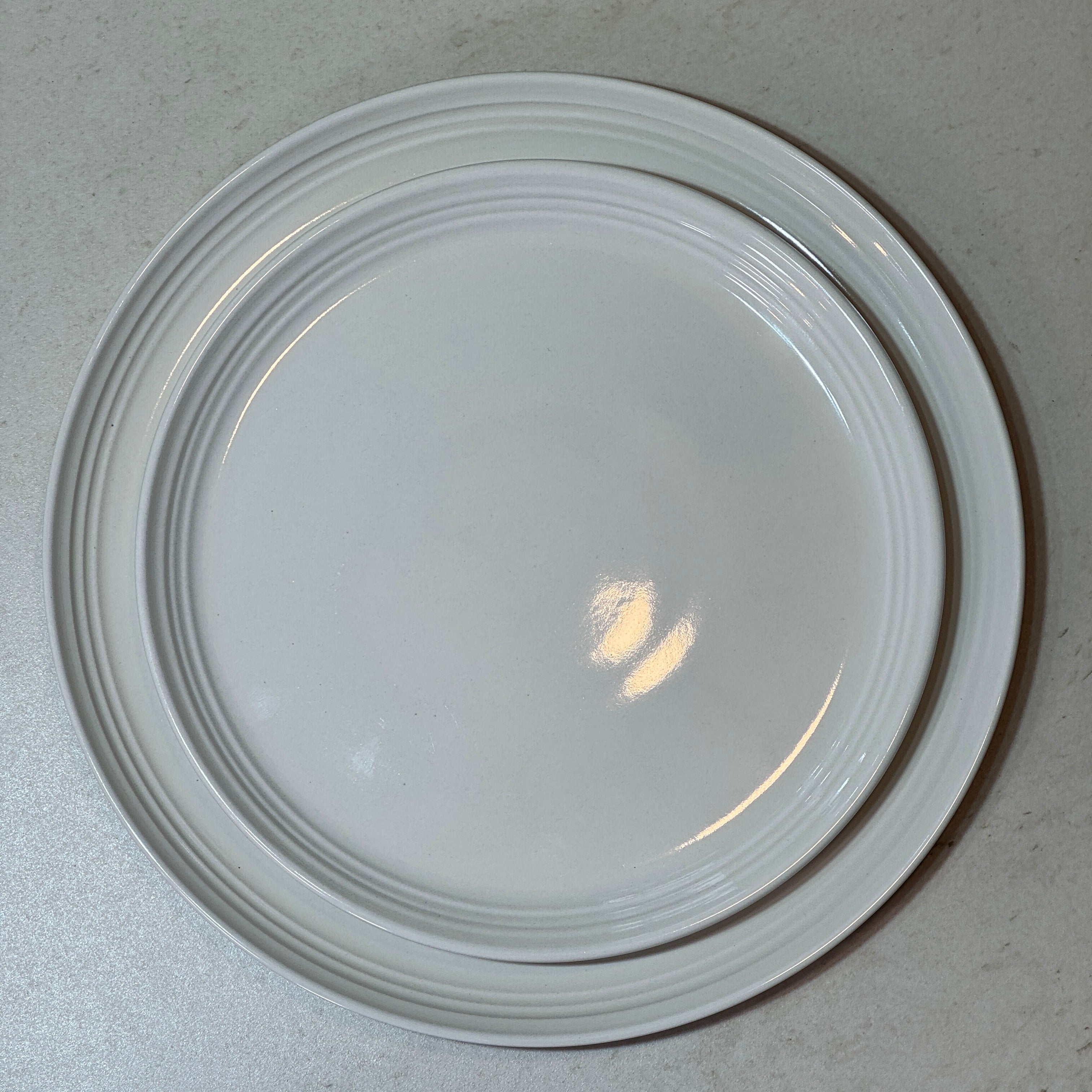 Service d'assiettes en céramique émaillée blanc comprenant une assiette plate 27 cm et une assiette à dessert 22 cm.