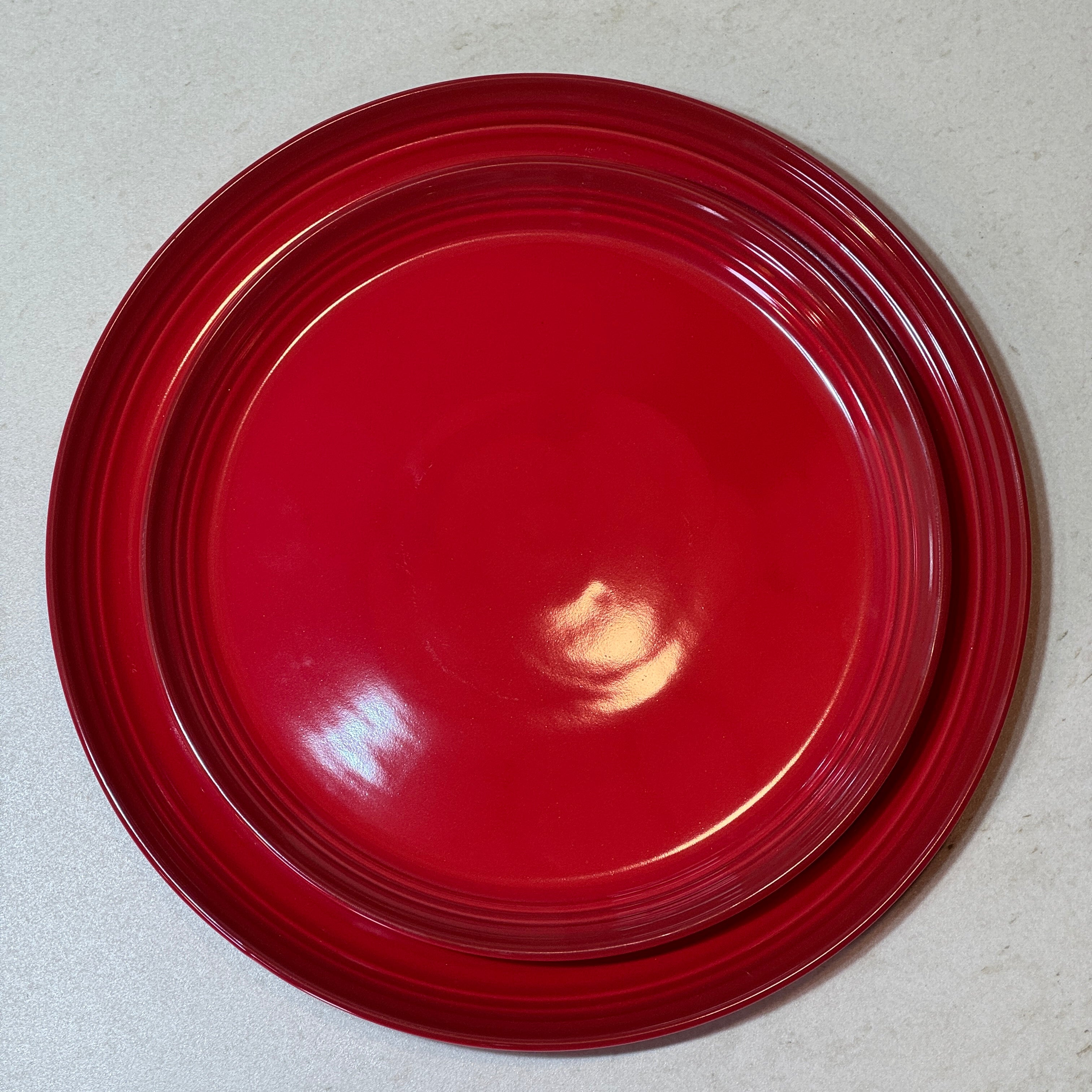 Service d'assiettes en céramique émaillée rouge comprenant une assiette plate 27 cm et une assiette à dessert 22 cm.
